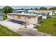 Home's beige siding is accented by green lawn and concrete driveway leading up to the front entrance at 37302 Carol Ave, Zephyrhills, FL 33542