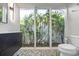 Stylish bathroom with unique pebble flooring and a window offering natural green views at 3956 Versailles Dr, Tampa, FL 33634