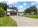 Long driveway leading to a contemporary two-story home with a dark garage door and manicured front yard at 3956 Versailles Dr, Tampa, FL 33634
