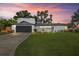Contemporary home featuring a well-manicured lawn and an attached garage against a dramatic sunset at 3956 Versailles Dr, Tampa, FL 33634