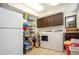 Well-lit laundry room with tiled floors, washer, dryer, utility sink, shelving, and cabinet space at 4205 Helene Pl, Valrico, FL 33594