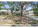 Quaint home with mature trees, manicured lawn, and a light yellow exterior under a blue sky at 4417 W El Prado Blvd, Tampa, FL 33629