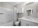 Bright bathroom features a shower-tub combo, cabinet storage, and a round mirror at 5000 Culbreath Key Way # 1-112, Tampa, FL 33611