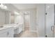 Elegant bathroom featuring double sinks, white cabinetry, a glass-enclosed shower, and access to a walk-in closet at 5178 Everlong Dr, Apollo Beach, FL 33572