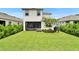 Large backyard featuring well-manicured lawn, mature landscaping, and a screened in patio at 5611 Del Coronado Dr, Apollo Beach, FL 33572