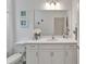 Bright bathroom featuring white cabinets, quartz counters, large mirror, and elegant decorative touches at 5611 Del Coronado Dr, Apollo Beach, FL 33572