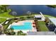 Aerial view showcasing a community pool with lounge chairs and umbrellas next to a lake at 5611 Del Coronado Dr, Apollo Beach, FL 33572