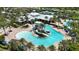 Aerial view showcasing a community pool with a slide, a splash pad, and lounge areas surrounded by palm trees at 5611 Del Coronado Dr, Apollo Beach, FL 33572