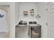 Modern laundry room featuring side-by-side, front-load washer and dryer, with storage shelf above at 5611 Del Coronado Dr, Apollo Beach, FL 33572