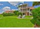 Scenic backyard featuring a fire pit seating area, lush lawn, and views of the multi-story condo at 6107 Marbella Blvd, Apollo Beach, FL 33572