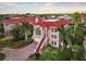 Elegant two-story home boasting a striking red tile roof, red door, grand entrance staircase, and lush tropical landscaping at 6107 Marbella Blvd, Apollo Beach, FL 33572