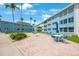 Courtyard with tables, umbrellas, chairs, blue buildings, and palm trees on a sunny day at 6161 Gulf Winds Dr # 347, St Pete Beach, FL 33706