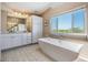 Bright bathroom featuring a tub, vanity, and a large window offering views of the surrounding landscape at 6186 Seaside Dr, New Port Richey, FL 34652