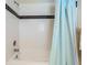 Bathtub with white tiles, black accent tiles, and a light blue shower curtain at 6186 Seaside Dr, New Port Richey, FL 34652