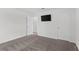 Bedroom with neutral walls, grey carpet, a television, and doors leading to other rooms at 6248 Bradford Woods Dr, Zephyrhills, FL 33542