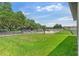 View of the front yard showcases lush green grass, mature trees, and a black metal fence at 6248 Bradford Woods Dr, Zephyrhills, FL 33542