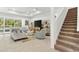 Bright and airy living room with neutral furniture, tile flooring, and staircase at 6248 Bradford Woods Dr, Zephyrhills, FL 33542