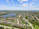 Sprawling aerial view showcasing a neighborhood situated by a lake, surrounded by extensive greenery and blue skies at 6467 Seasound Dr, Apollo Beach, FL 33572