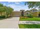 Inviting single-Gathering home featuring a manicured lawn, colorful flowerbeds, and a two-car garage at 6467 Seasound Dr, Apollo Beach, FL 33572
