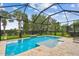 Inviting screened-in pool with a shallow sun shelf, surrounded by travertine pavers and lush landscaping at 6467 Seasound Dr, Apollo Beach, FL 33572