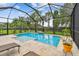Screened-in pool area featuring travertine decking, landscaping, and a comfortable spot to relax at 6467 Seasound Dr, Apollo Beach, FL 33572