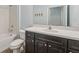 Bathroom with dark vanity, white countertop, a built-in bathtub, and a mounted mirror at 6706 Riverside Bluffs Dr, Riverview, FL 33578