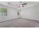 A bright bedroom with a ceiling fan, gray carpet, and natural light from two windows at 6706 Riverside Bluffs Dr, Riverview, FL 33578