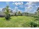 Lush backyard features a green lawn, mature trees, and a white fence for privacy at 7517 Notched Pine Bnd, Wesley Chapel, FL 33545