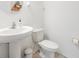 Cozy half bathroom featuring a pedestal sink, toilet, and a decorative round mirror at 7517 Notched Pine Bnd, Wesley Chapel, FL 33545