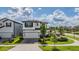 Exterior view of a two-story home with manicured lawn, brick driveway, and well-maintained landscaping at 7517 Notched Pine Bnd, Wesley Chapel, FL 33545