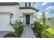 Charming front door entry with paved walkway, lush landscaping, and neutral-colored exterior at 7517 Notched Pine Bnd, Wesley Chapel, FL 33545