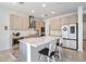 Modern kitchen boasts light wood cabinets, stainless appliances, and a white marbled island with bar seating at 7517 Notched Pine Bnd, Wesley Chapel, FL 33545