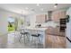 Bright kitchen area with an island, bar stools, stainless appliances, and a view of the backyard at 7517 Notched Pine Bnd, Wesley Chapel, FL 33545