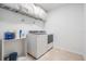 Bright laundry room with modern washer and dryer, tile floor, and storage shelf, offering convenience and functionality at 7517 Notched Pine Bnd, Wesley Chapel, FL 33545