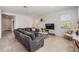 Bright living room featuring a gray sectional sofa, tile floors, and a contemporary design at 7517 Notched Pine Bnd, Wesley Chapel, FL 33545