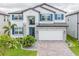Beautiful two-story home featuring stone accents, blue shutters, and a paved driveway at 7700 Bronze Oak Dr, Wesley Chapel, FL 33545