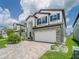 Inviting two-story home with stone accents, blue shutters, and paver driveway at 7700 Bronze Oak Dr, Wesley Chapel, FL 33545