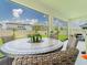 A screened patio features a round stone table with seating and a backyard view at 7700 Bronze Oak Dr, Wesley Chapel, FL 33545