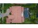Aerial view of a luxurious home with a red tiled roof, screened pool, patio, and manicured landscaping at 8358 Dunham Station Dr, Tampa, FL 33647