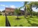 Spacious fenced backyard features a lush lawn, tropical trees, and a screened lanai perfect for outdoor living at 8358 Dunham Station Dr, Tampa, FL 33647