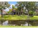Backyard view of a black metal fence, mature trees, green lawn, and a peaceful pond at 8358 Dunham Station Dr, Tampa, FL 33647