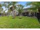 Expansive backyard showcasing a well-maintained lawn, mature palm trees, and a screened lanai with outdoor seating at 8358 Dunham Station Dr, Tampa, FL 33647