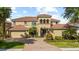 Charming two-story home with lush landscaping, a brick driveway, and attached garage at 8358 Dunham Station Dr, Tampa, FL 33647