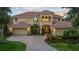 Imposing two-story home featuring manicured landscaping, a brick paver driveway, and a three-car garage at 8358 Dunham Station Dr, Tampa, FL 33647