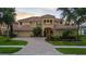 Elegant two-story home with a well-manicured lawn, brick driveway, and beautiful landscaping at 8358 Dunham Station Dr, Tampa, FL 33647