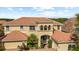Stately two-story home with a terracotta roof, arched entryway, manicured landscaping, and a brick paver driveway at 8358 Dunham Station Dr, Tampa, FL 33647