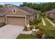 Charming home showcasing attached garage, lush landscaping, and stone pillar accents at 8624 Snowy Owl Way, Tampa, FL 33647