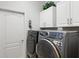 Modern laundry room features front load washer and dryer and white overhead cabinets at 8624 Snowy Owl Way, Tampa, FL 33647
