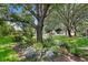 Landscaped front yard featuring a variety of plants, hanging baskets, and mature trees at 8624 Snowy Owl Way, Tampa, FL 33647