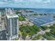 Expansive aerial view capturing a modern residential high-rise overlooking a serene marina and bay, with city skyline backdrop at 1 Beach Se Dr # 811, St Petersburg, FL 33701